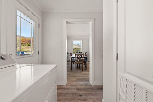 laundry room with a healthy amount of sunlight, dark hardwood / wood-style flooring, crown molding, and washing machine and clothes dryer