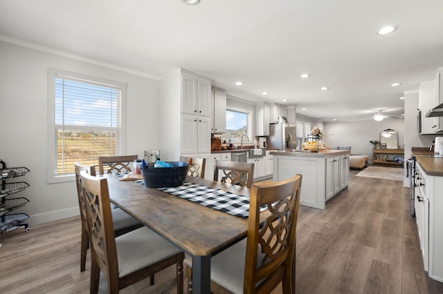 dining room with light hardwood / wood-style floors, sink, and crown molding