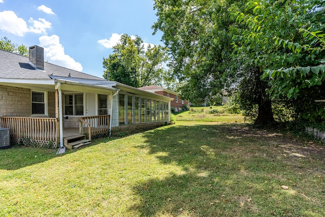 view of yard with central AC, a wooden deck, and a sunroom