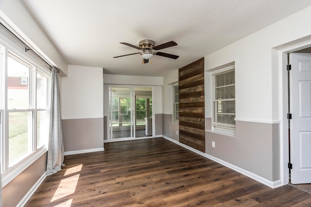 empty room featuring ceiling fan, a healthy amount of sunlight, and dark hardwood / wood-style flooring