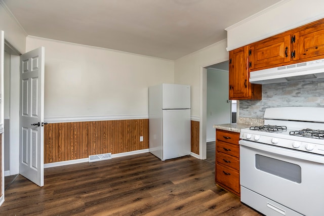 kitchen with crown molding, dark hardwood / wood-style flooring, white appliances, and wooden walls