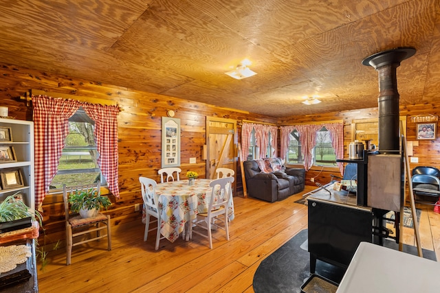 dining area with light wood-type flooring, wood ceiling, and wood walls