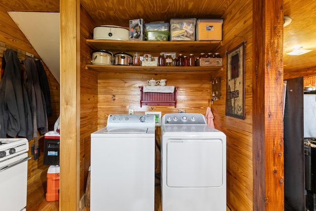 laundry room featuring wood walls, hardwood / wood-style floors, and washer and dryer