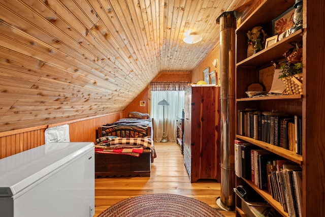 bedroom with light wood-type flooring, refrigerator, wood ceiling, vaulted ceiling, and wood walls