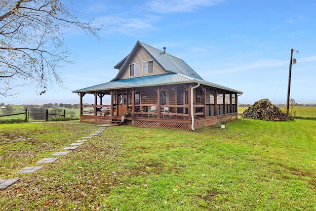 back of property with a lawn, a sunroom, and a rural view