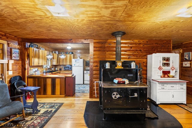 kitchen featuring white cabinets, white fridge, light hardwood / wood-style flooring, and log walls