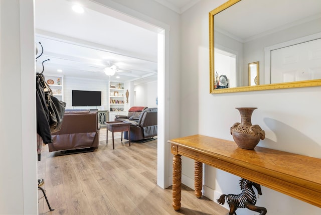 corridor featuring built in shelves, light wood-type flooring, and crown molding