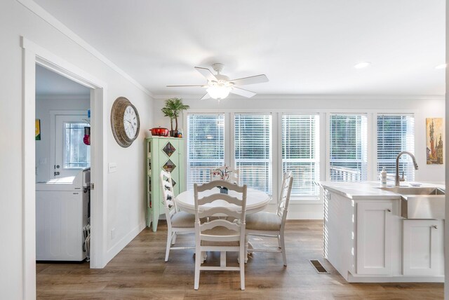 dining room with ornamental molding, ceiling fan, sink, light hardwood / wood-style flooring, and washer / clothes dryer