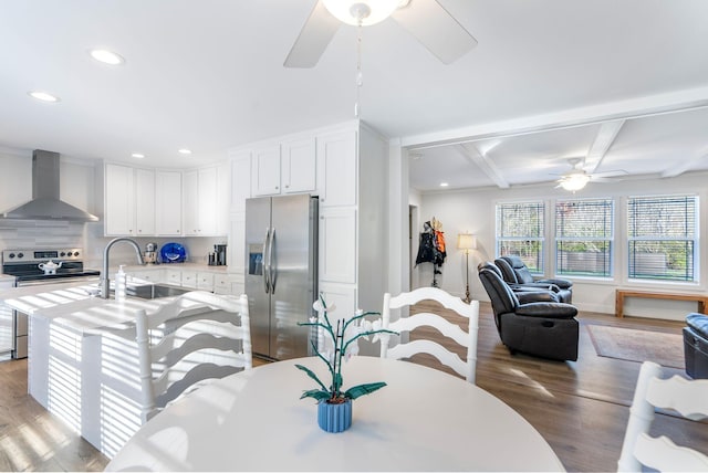 dining space featuring beamed ceiling, light wood-type flooring, ceiling fan, and sink