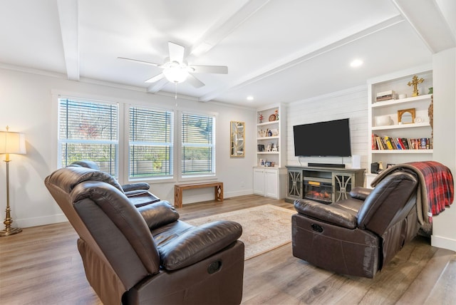 living room with crown molding, ceiling fan, light hardwood / wood-style floors, a fireplace, and beam ceiling