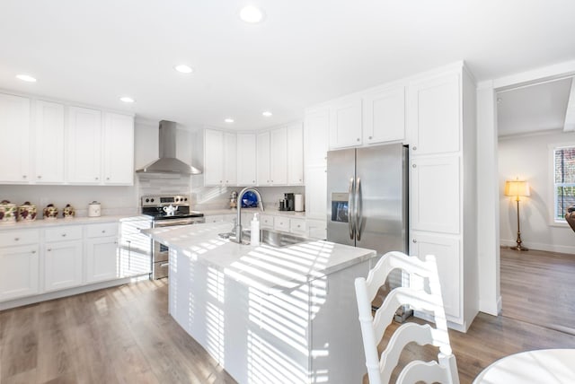 kitchen with stainless steel appliances, light hardwood / wood-style floors, wall chimney exhaust hood, and sink