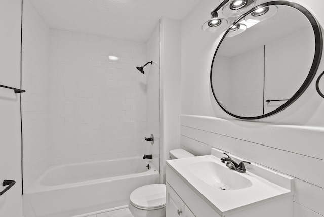 full bathroom with a textured ceiling, vanity, toilet, and tiled shower / bath