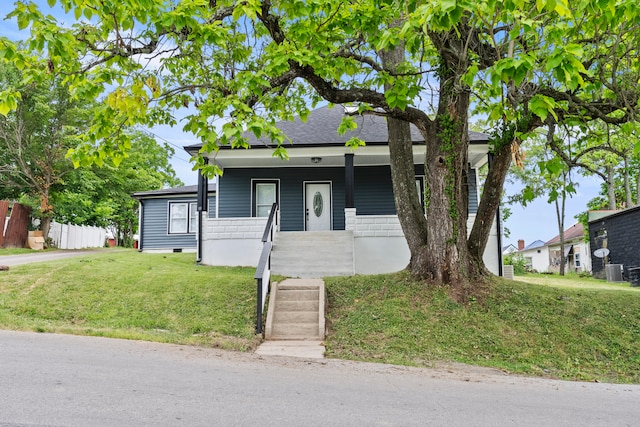 view of front of house featuring covered porch, central air condition unit, and a front yard