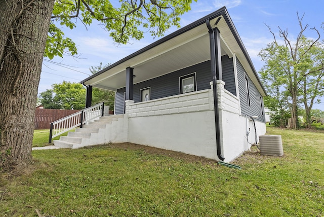 view of property exterior with a lawn, covered porch, and central AC unit