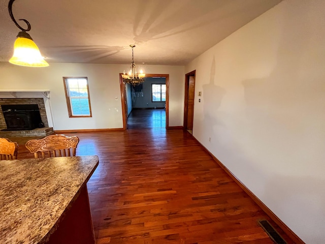 dining space with dark wood-type flooring, a brick fireplace, and a notable chandelier