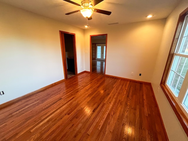 unfurnished room with a healthy amount of sunlight, ceiling fan, and wood-type flooring