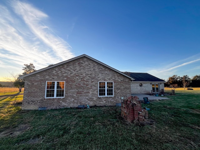 property exterior at dusk with a patio area and a yard