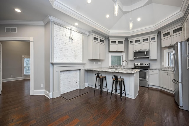 kitchen with light stone counters, visible vents, a peninsula, ornamental molding, and stainless steel appliances