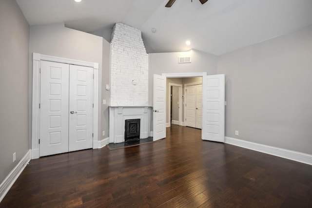 unfurnished living room with visible vents, lofted ceiling, dark wood-style flooring, ceiling fan, and a large fireplace