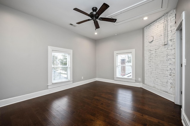 unfurnished room featuring baseboards, visible vents, attic access, ceiling fan, and dark wood-type flooring