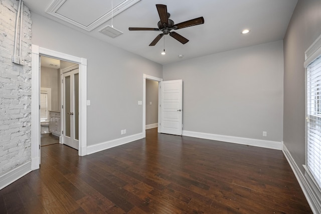 unfurnished bedroom featuring visible vents, baseboards, attic access, and dark wood-style floors