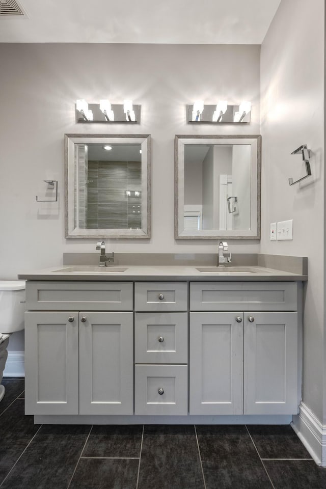 bathroom with double vanity, toilet, tile patterned floors, and a sink