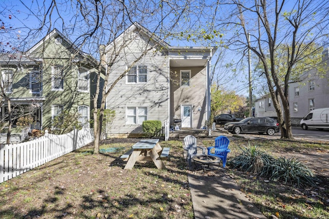 back of house featuring an outdoor fire pit and fence