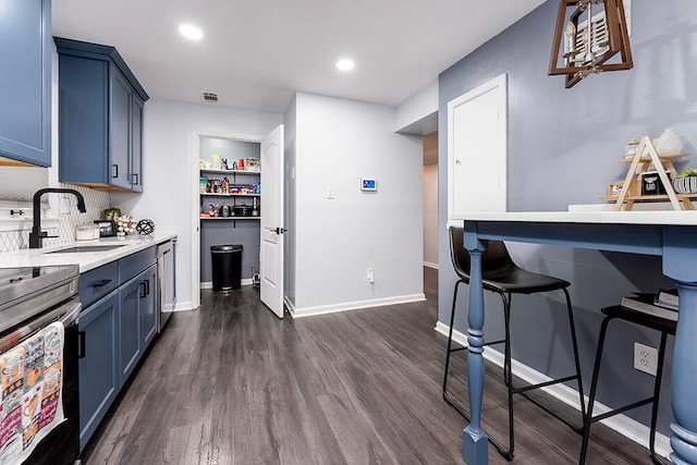 kitchen featuring decorative backsplash, sink, blue cabinets, and dark wood-type flooring