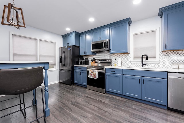 kitchen with appliances with stainless steel finishes, dark hardwood / wood-style flooring, blue cabinets, and sink