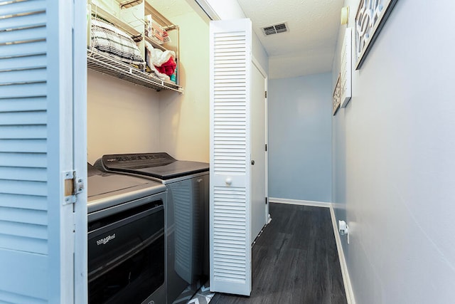 clothes washing area with separate washer and dryer, dark hardwood / wood-style flooring, and a textured ceiling