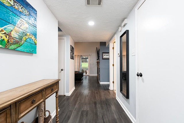 hall with a textured ceiling and dark wood-type flooring