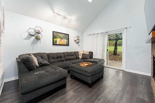 living room with dark hardwood / wood-style floors, rail lighting, and high vaulted ceiling