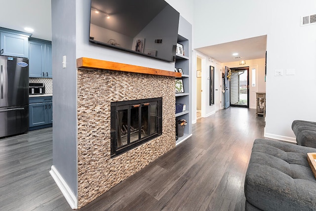 living room featuring built in shelves and dark wood-type flooring