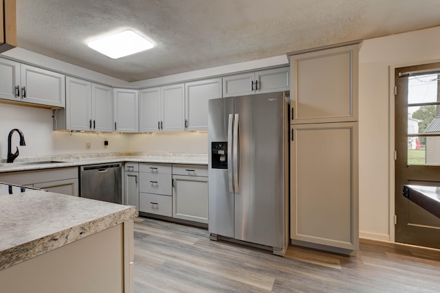 kitchen with gray cabinets, light hardwood / wood-style floors, sink, and stainless steel appliances