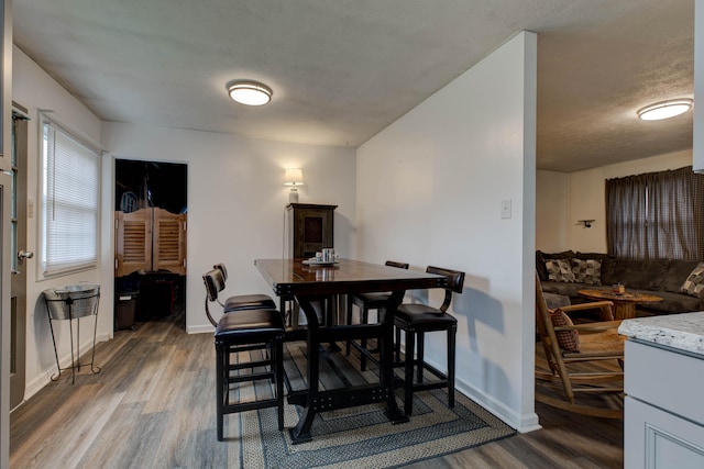 dining space with wood-type flooring and a textured ceiling