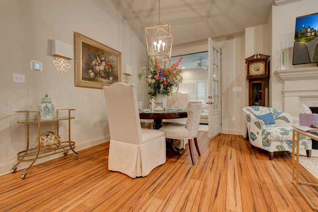 dining area featuring ceiling fan with notable chandelier, light hardwood / wood-style floors, and a high ceiling