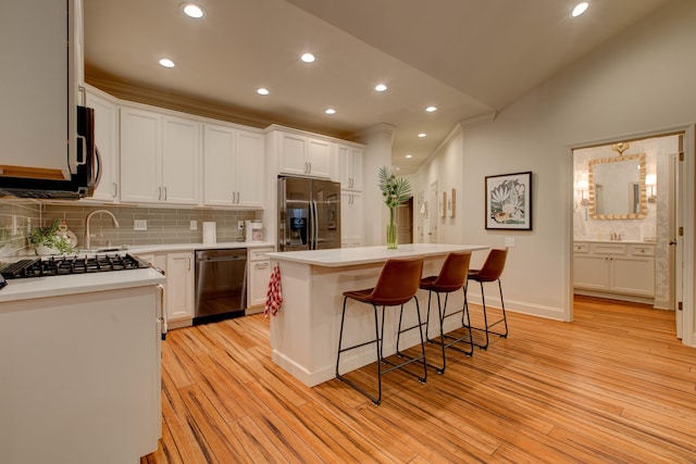 kitchen featuring appliances with stainless steel finishes, light wood-type flooring, white cabinetry, and a kitchen island