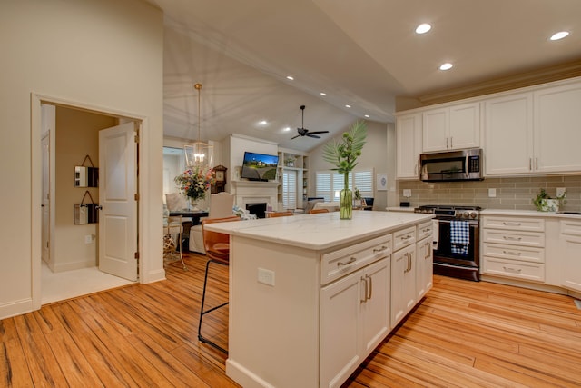 kitchen featuring stainless steel appliances, ceiling fan, white cabinets, light hardwood / wood-style floors, and lofted ceiling