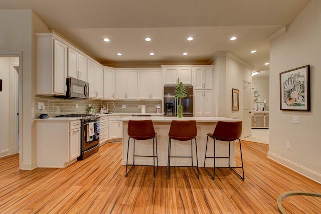 kitchen with white cabinets, appliances with stainless steel finishes, light wood-type flooring, and a center island