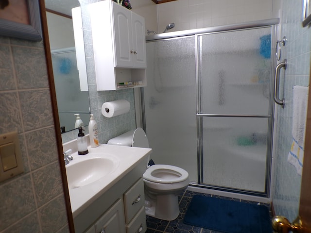 bathroom featuring walk in shower, tile patterned floors, toilet, vanity, and tile walls