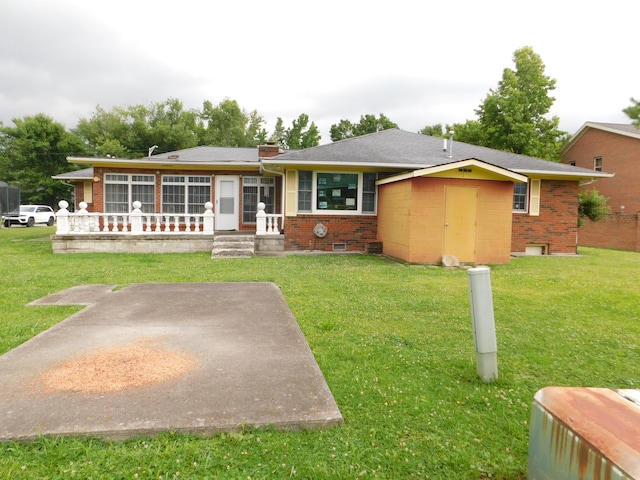 ranch-style house featuring a front lawn, a storage unit, and a patio area