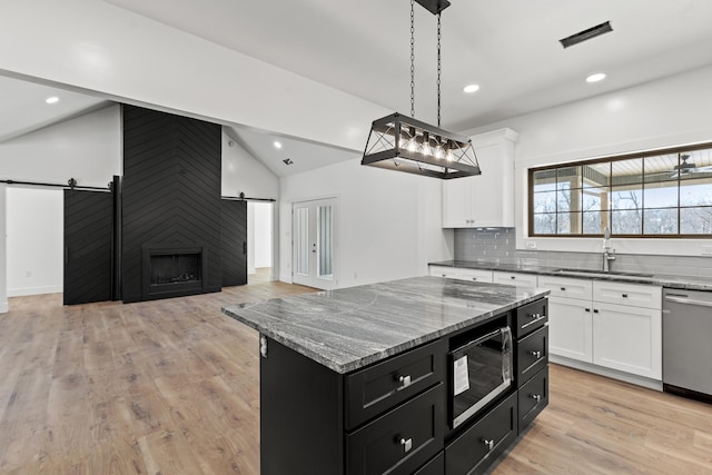 kitchen featuring a barn door, sink, a kitchen island, and black microwave