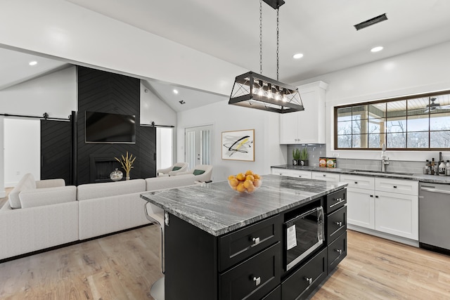 kitchen with black microwave, sink, a barn door, and a center island