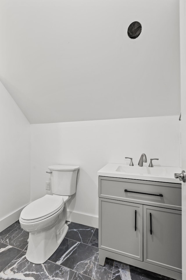 bathroom featuring lofted ceiling, vanity, and toilet