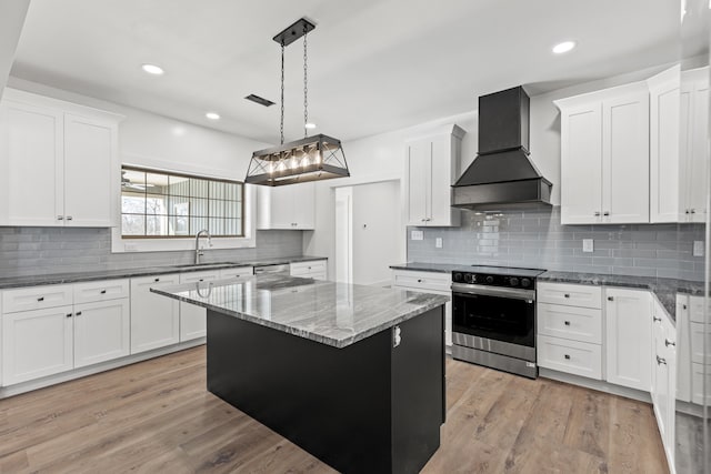 kitchen with stainless steel electric range oven, premium range hood, white cabinets, hanging light fixtures, and a center island