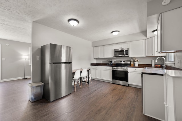 kitchen featuring white cabinets, sink, appliances with stainless steel finishes, and dark wood-type flooring