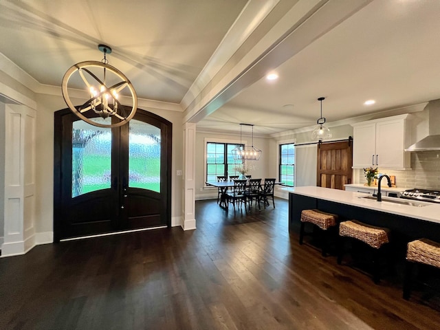 entrance foyer featuring sink, crown molding, dark hardwood / wood-style floors, a barn door, and a notable chandelier