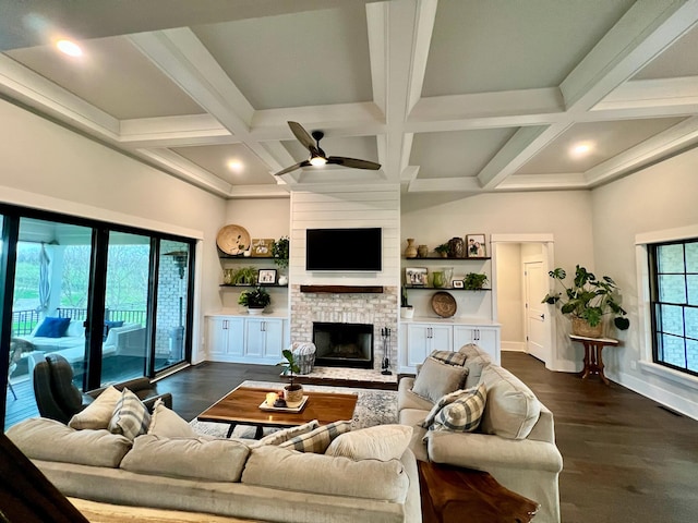 living room featuring dark hardwood / wood-style flooring, coffered ceiling, ceiling fan, beam ceiling, and a fireplace