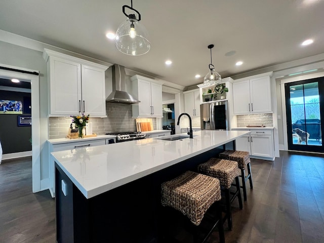 kitchen featuring dark hardwood / wood-style flooring, stainless steel appliances, wall chimney range hood, pendant lighting, and white cabinetry