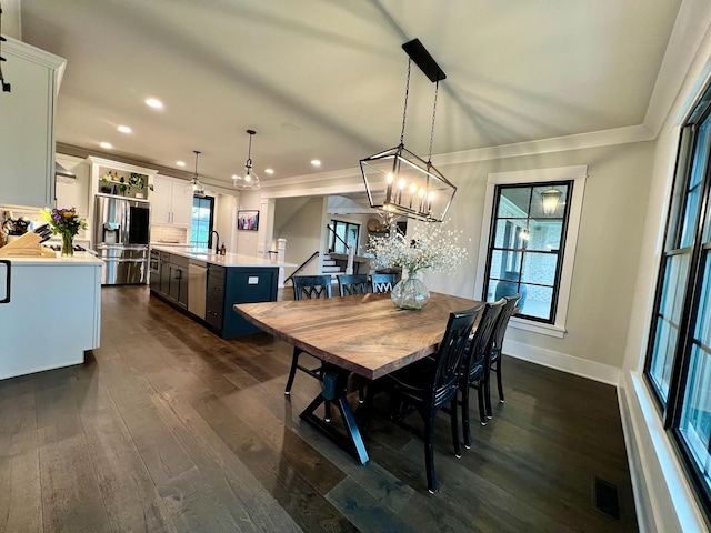 dining space featuring crown molding, sink, dark hardwood / wood-style floors, and a notable chandelier